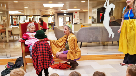 Juf Annette en twee kinderen in de rol van prins en prinses tijdens het thema sprookjes.